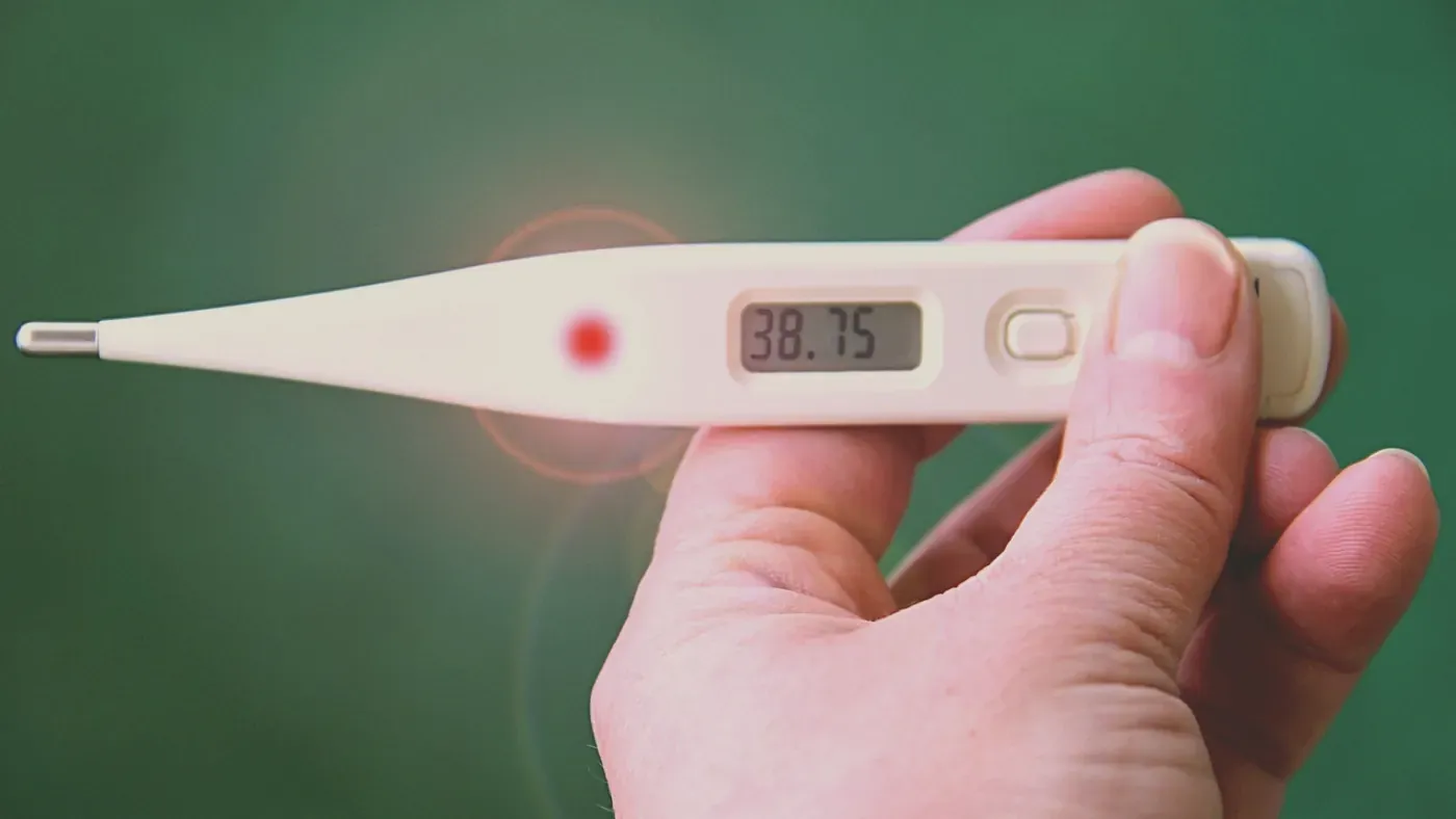 Digital febertermometer som visar 38,75 grader i en hand