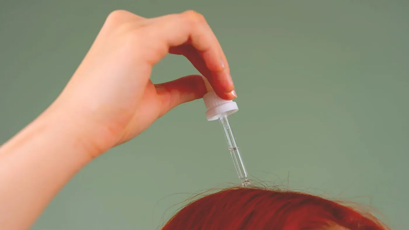 Hand som applicerar serum med pipett i en hårbena