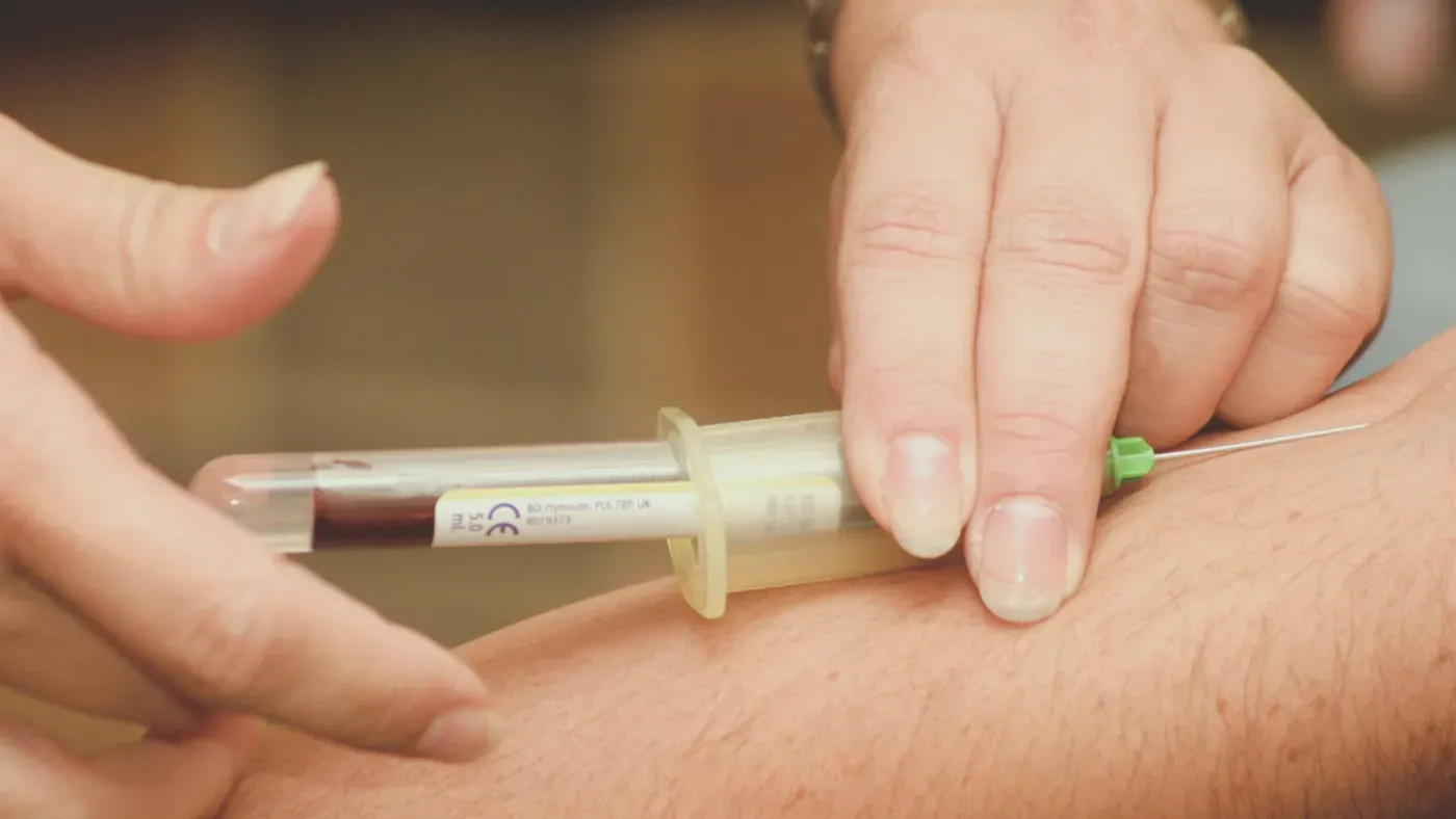 Blodprov tas med nål och provrör ur armen på en patient