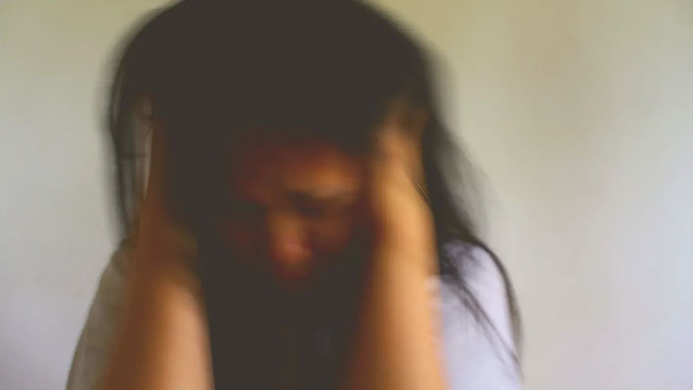Kvinna med händerna mot huvudet i en stressad, uppgiven gest