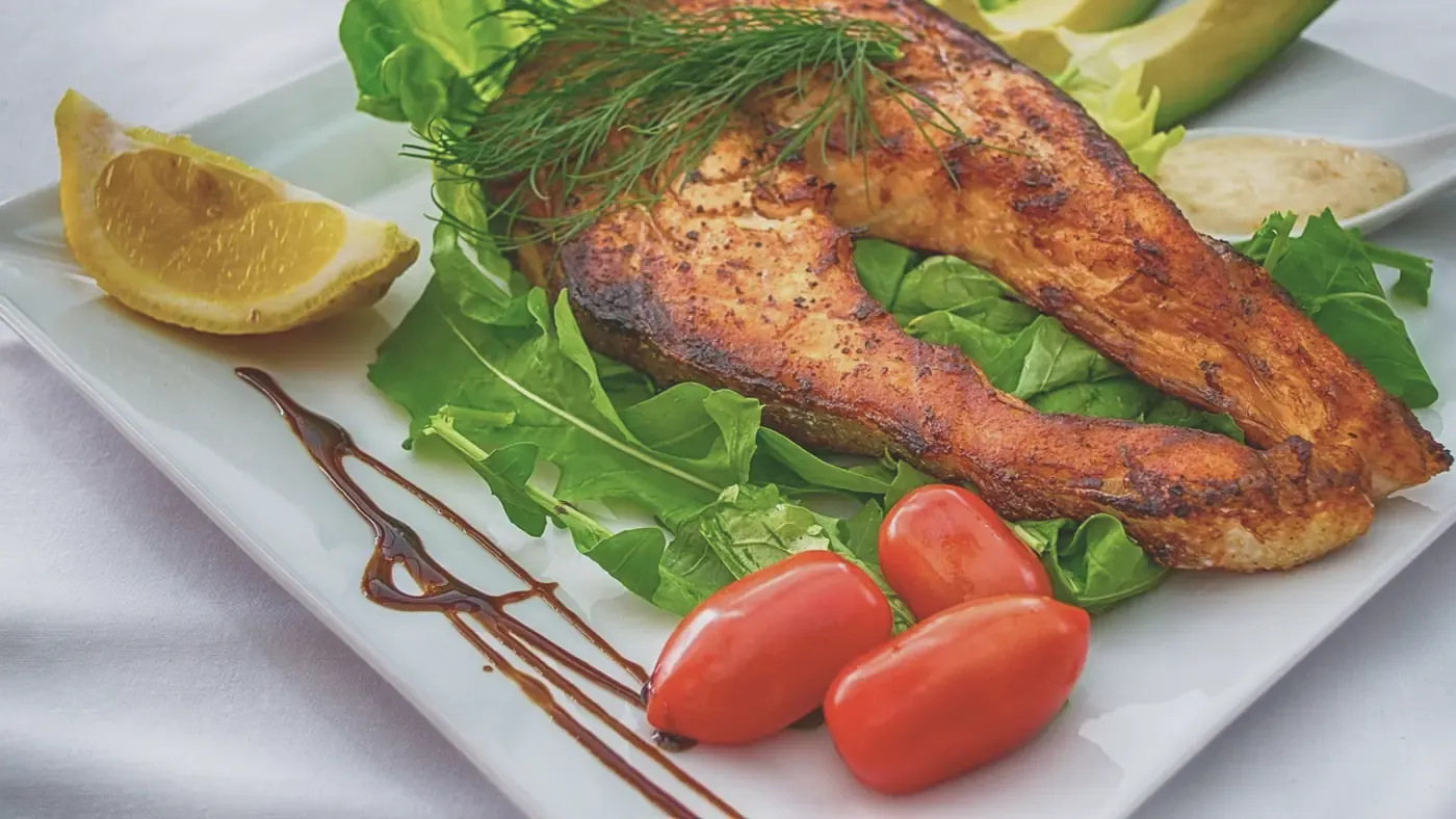 Tallrik med grillad lax, sallad, avokado och tomat – ett exempel på balanserad kost